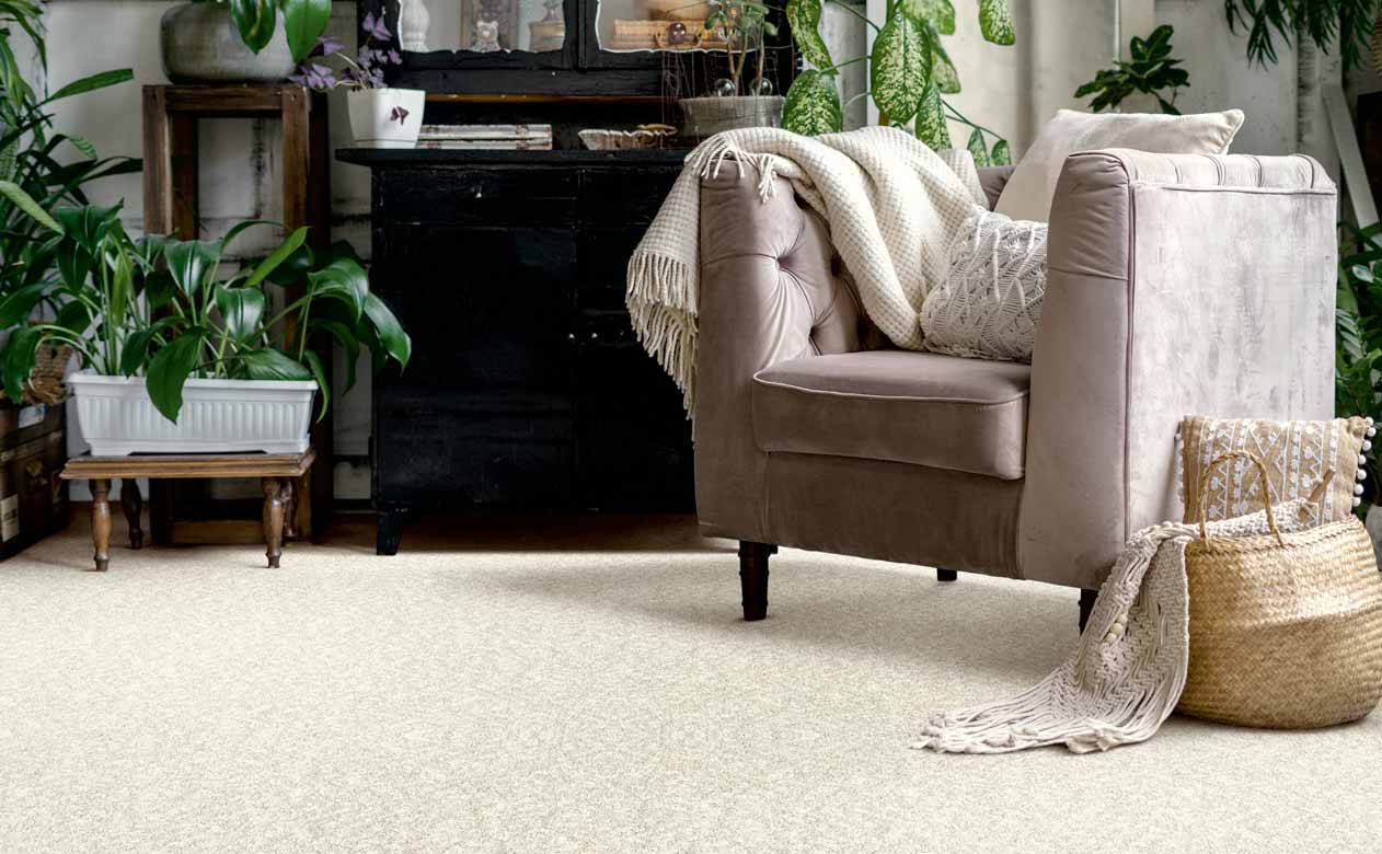 Living room with brown chair, ottoman, and dresser with beige carpet